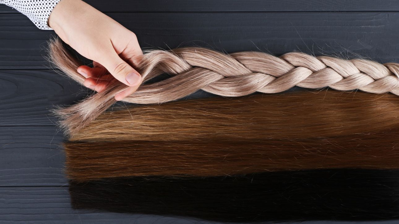 Man holds by his hand different types of hair for extensions.