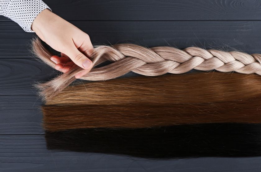 Man holds by his hand different types of hair for extensions.