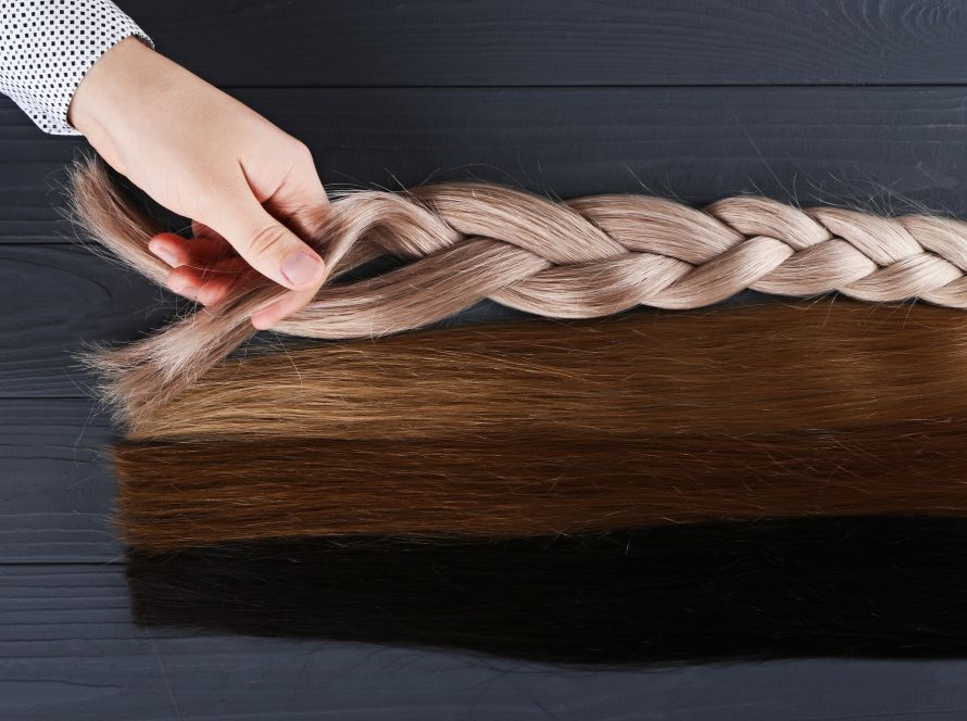 Man holds by his hand different types of hair for extensions.